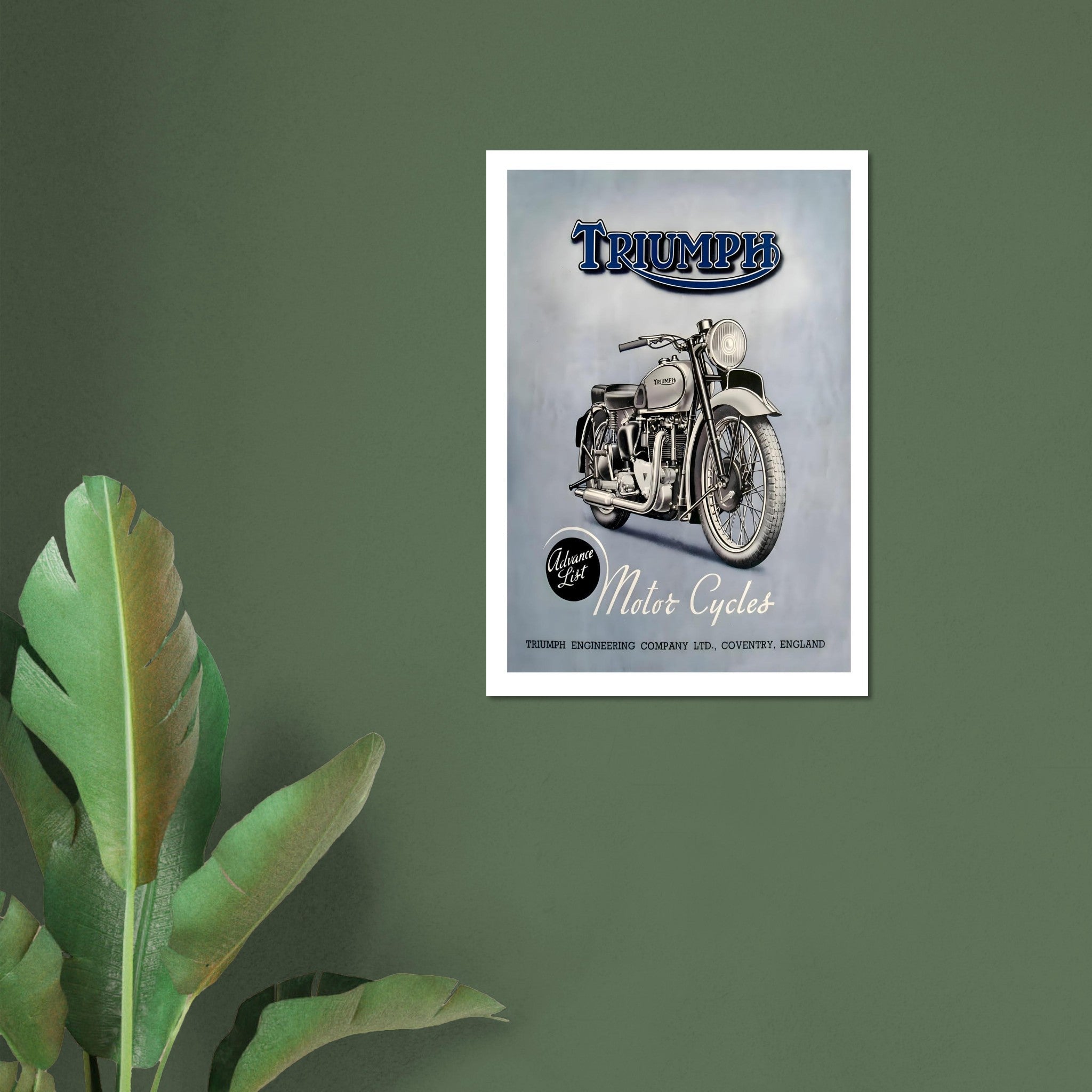 vintage Triumph motorcycle poster framed on a wall with green background and palm leaves.